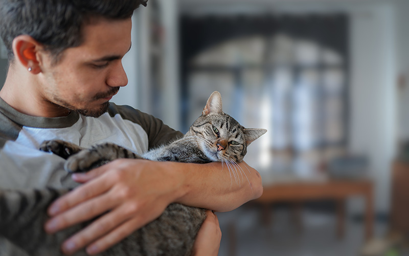 Surprise and delight your customers through agent empowerment to foster brand loyalty, increase satisfaction - Young Man Holds Tabby Cat