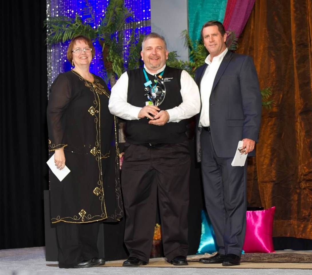 David May recieves his Mojo Award during the Arabian Nights dinner at ICUC 2013. L to R Sarah McElwee, KMB Group; David May, Schumacher Group; Greg Ayers, NICE CXone