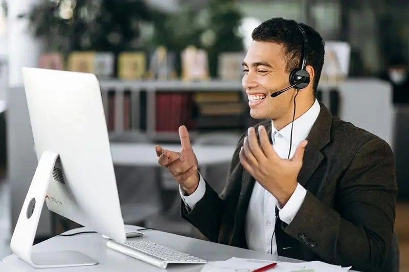 a man wearing headphones and sitting at a desk with a laptop