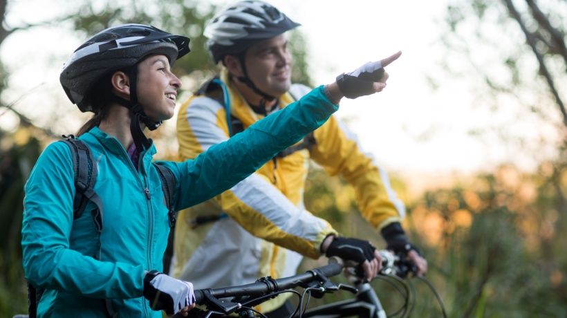 Biker couple on a trail, pointing ahead, showcasing adventure with the NICE CXone platform.