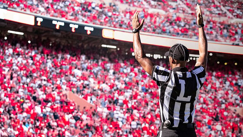 American Football Referee official signals a touchdown in a large football stadium.