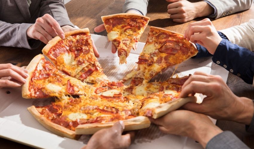 Businesspeople taking slice of pizza