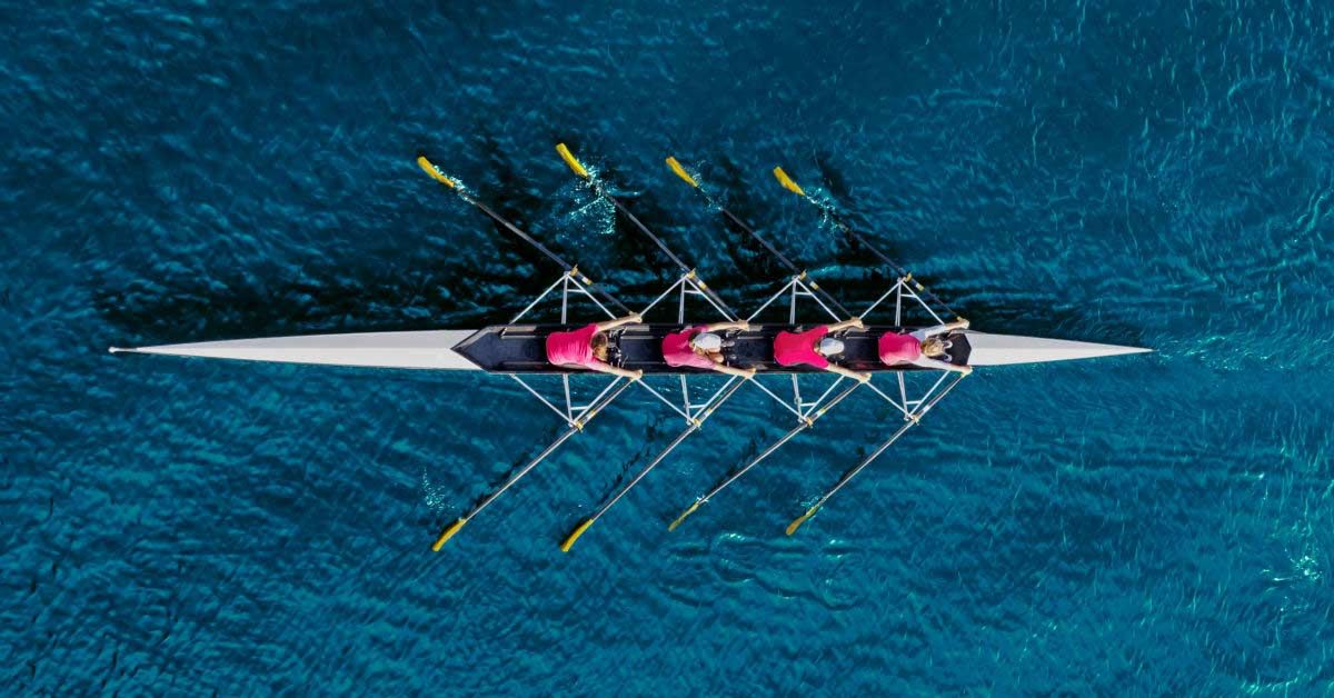 How CX decision-makers can collaborate to go the distance to cross the customer journey finish line first - Women's rowing team on blue water, top view
