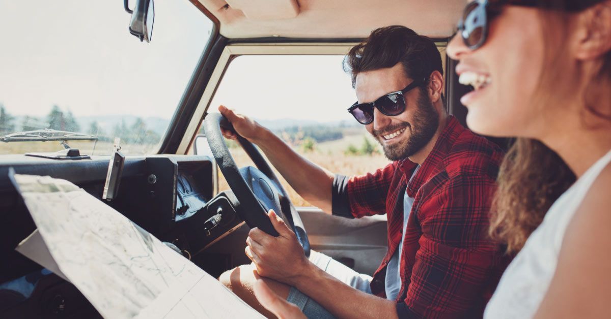 Happy young couple with a map in the car