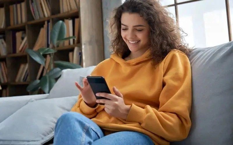 Teen girl checking social media holding smartphone at home